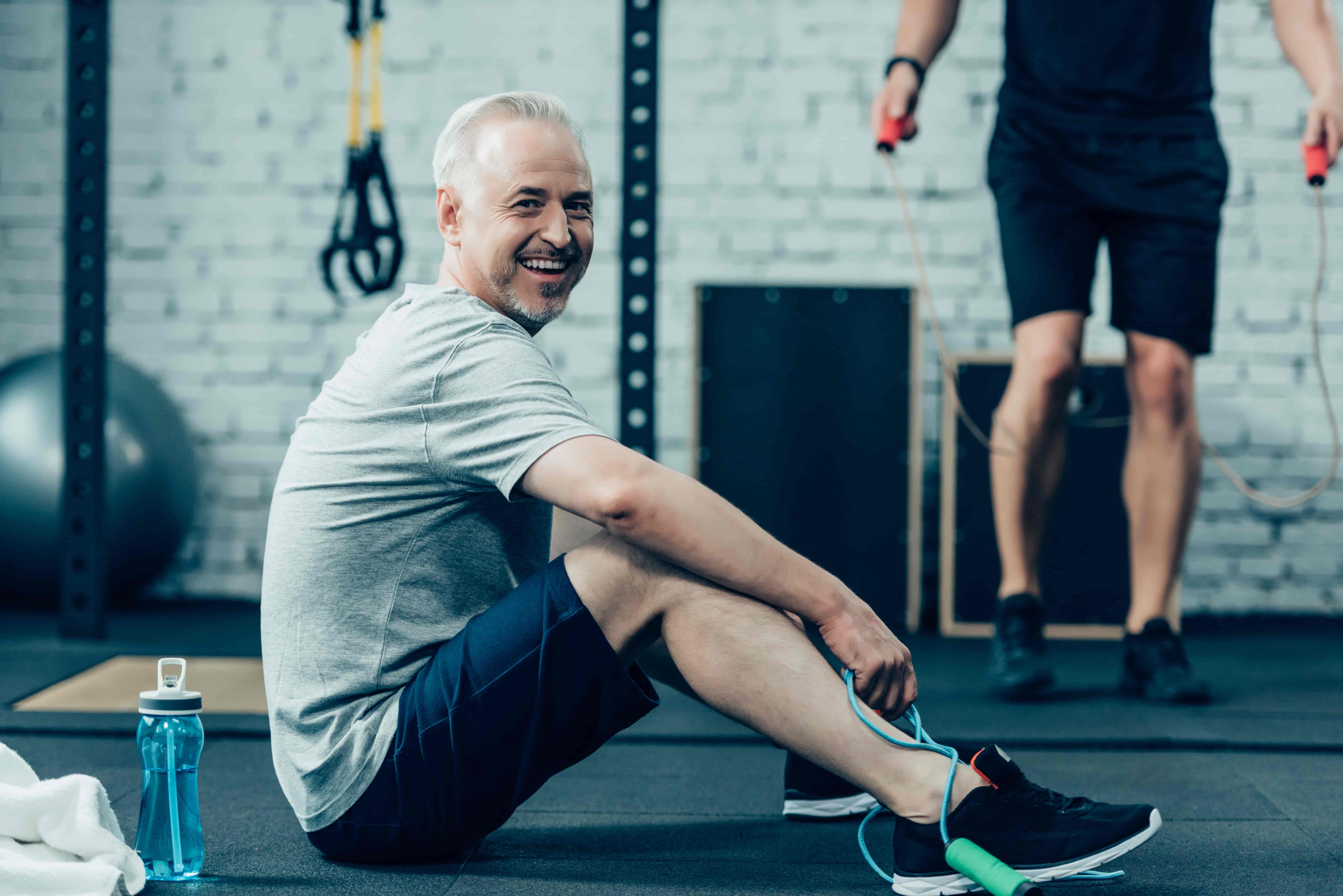 Man smiling as he catches his breath sitting on a gym floor