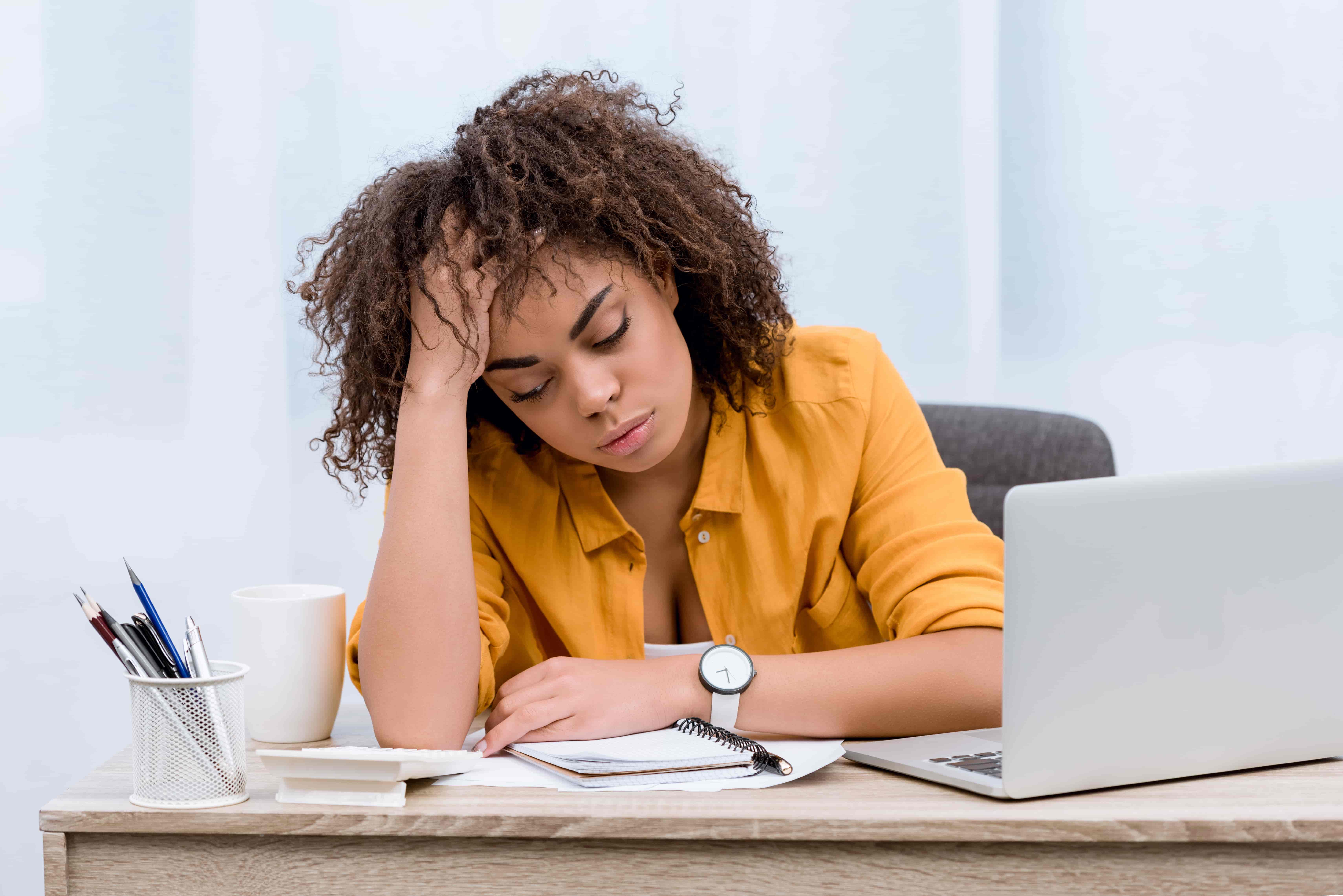 sleep deprived young woman sitting at workplace in office