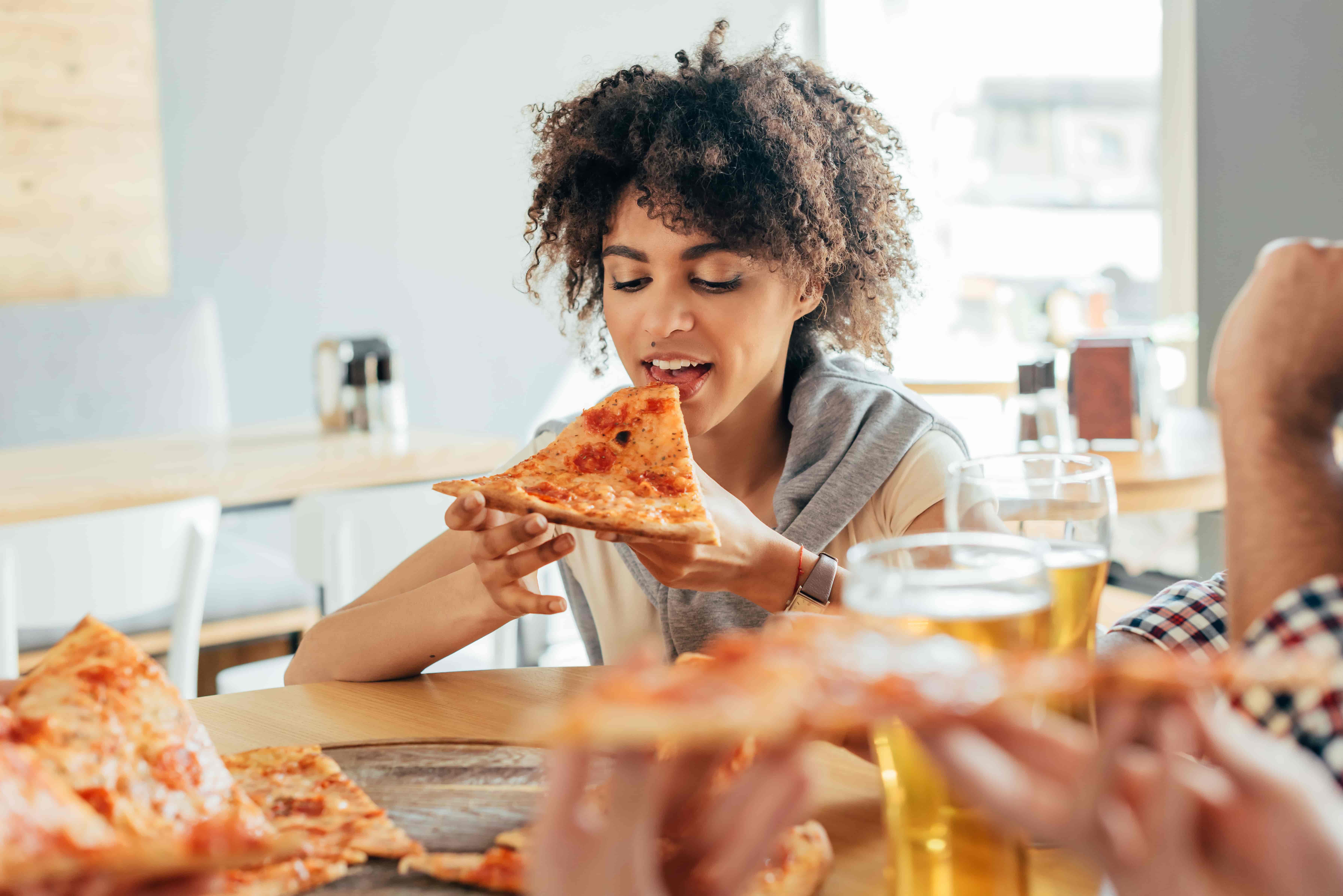 woman eating pizza and drinking beer
