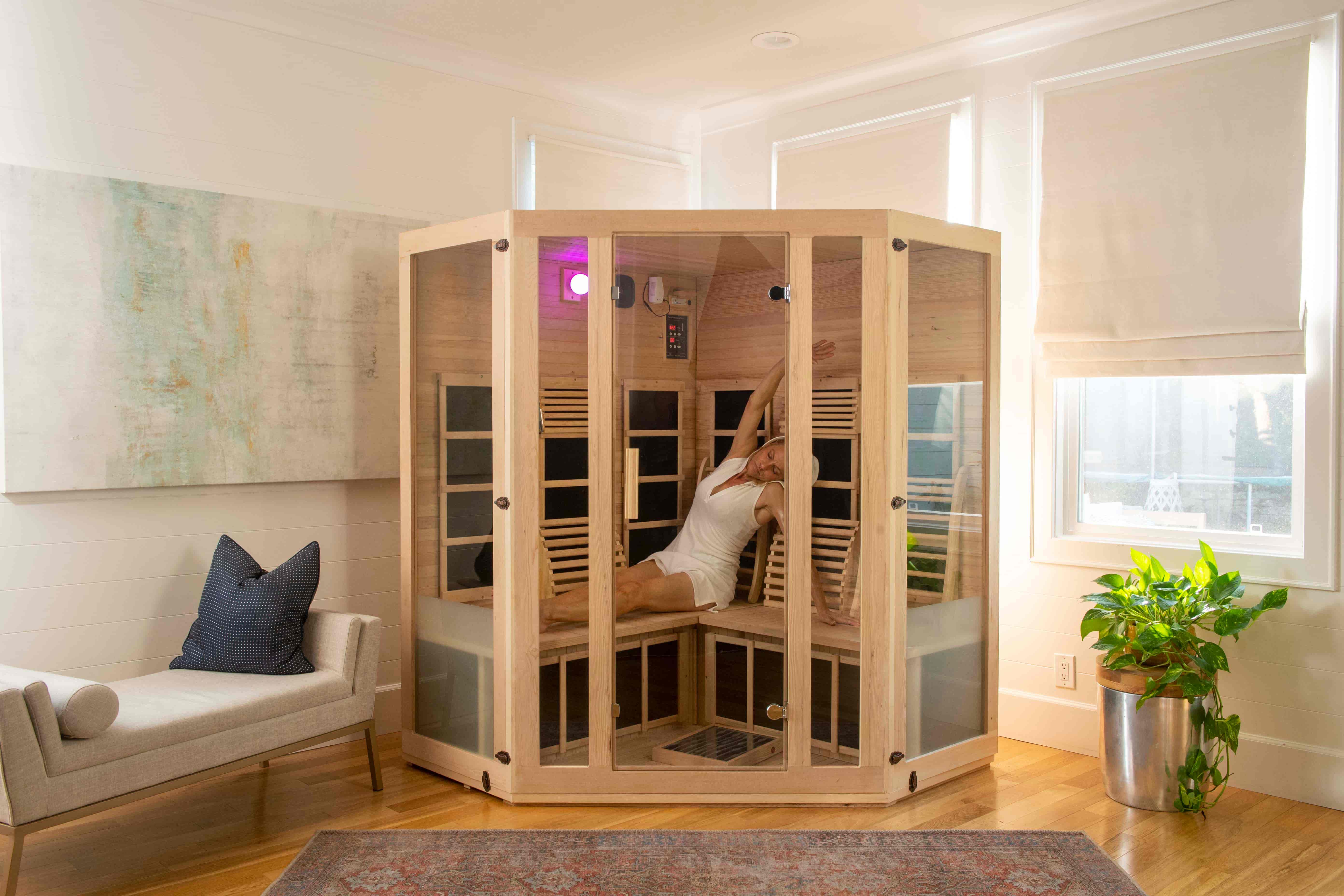 woman stretching during an infrared therapy session inside a joyous corner infrared sauna by JNH Lifestyles